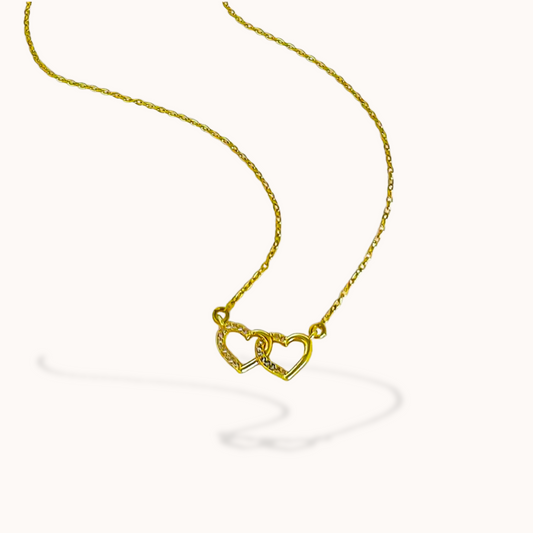 Gold necklace with a heart-shaped pendant on a white background