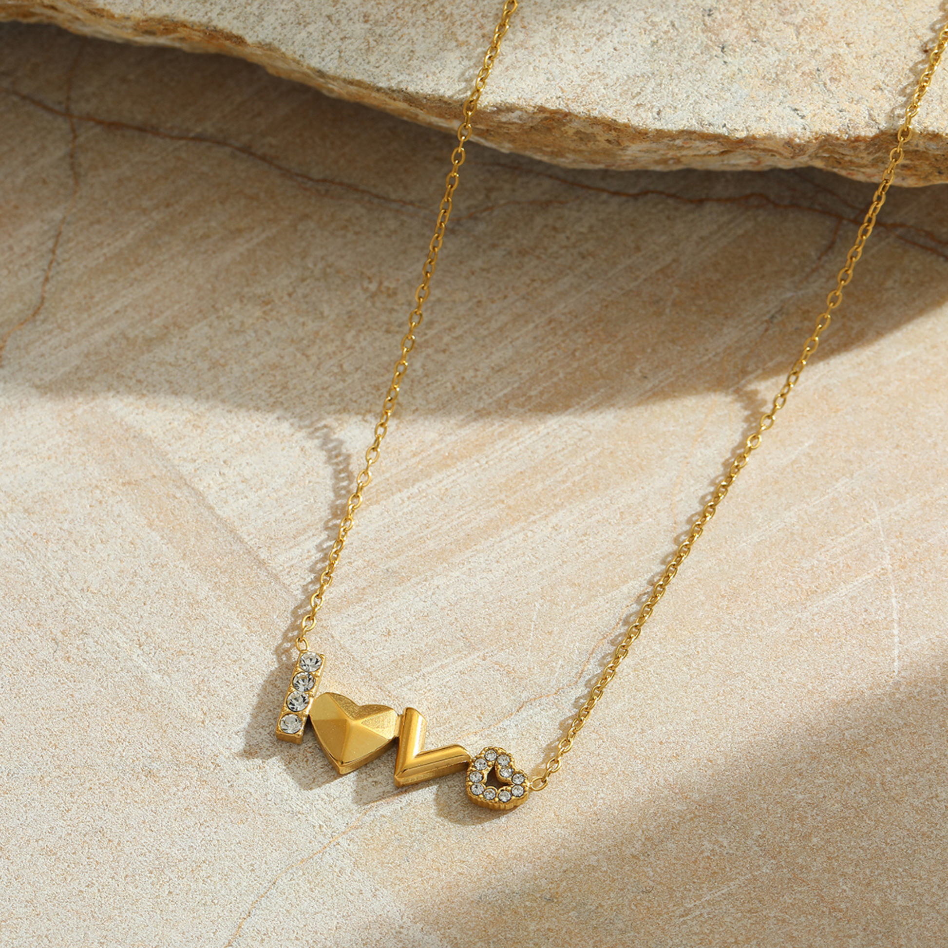 Gold necklace with heart-shaped pendants on a stone surface