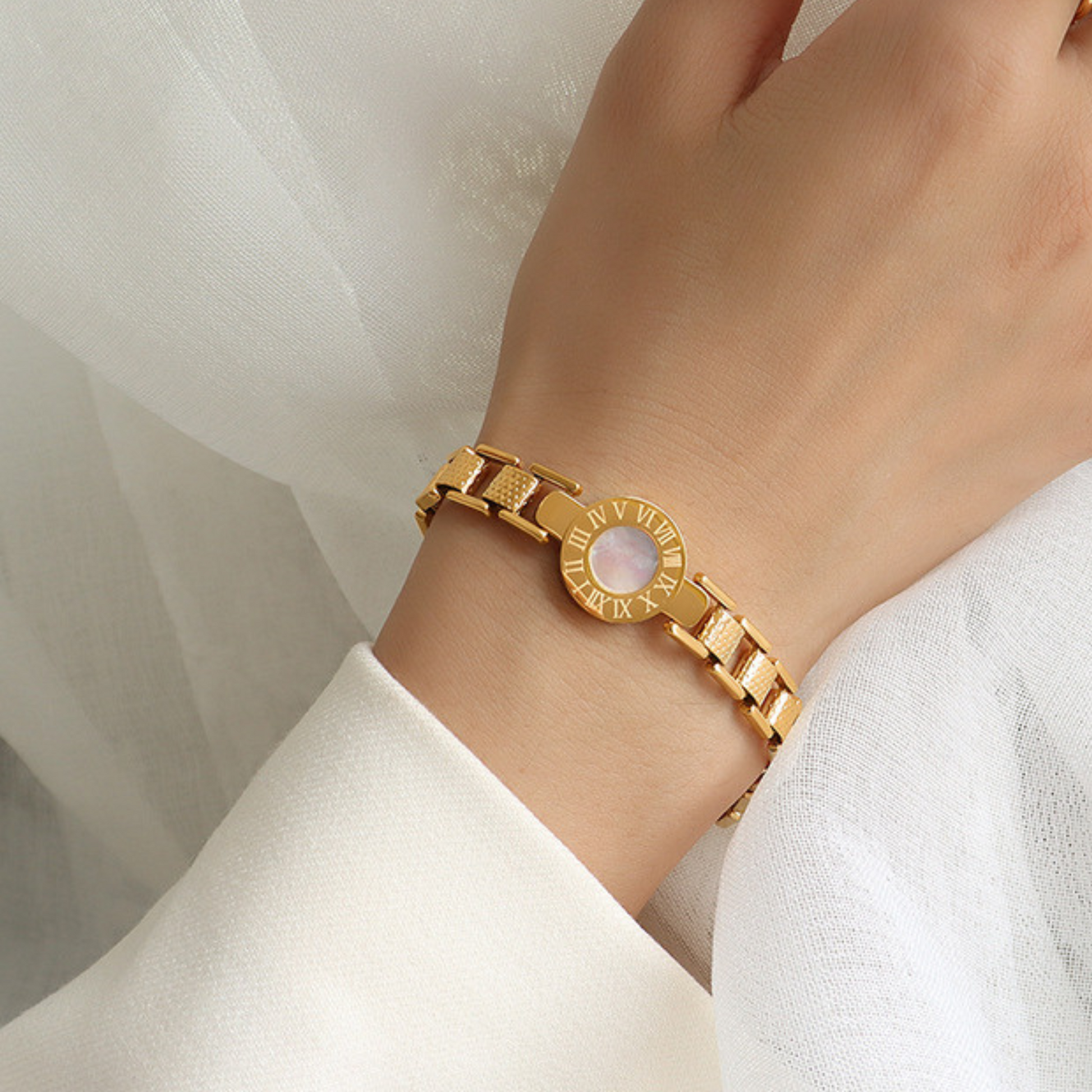 Gold bracelet with a circular design on a wrist against a white background