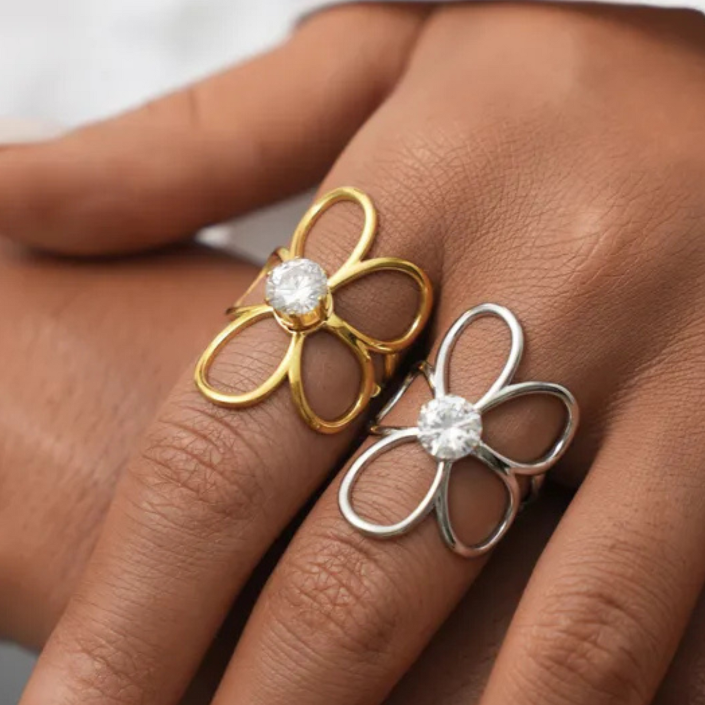 Gold and silver flower-shaped rings on a person's finger