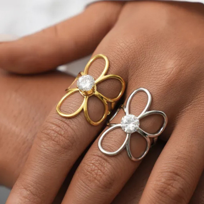 Gold and silver flower-shaped rings on a person's finger