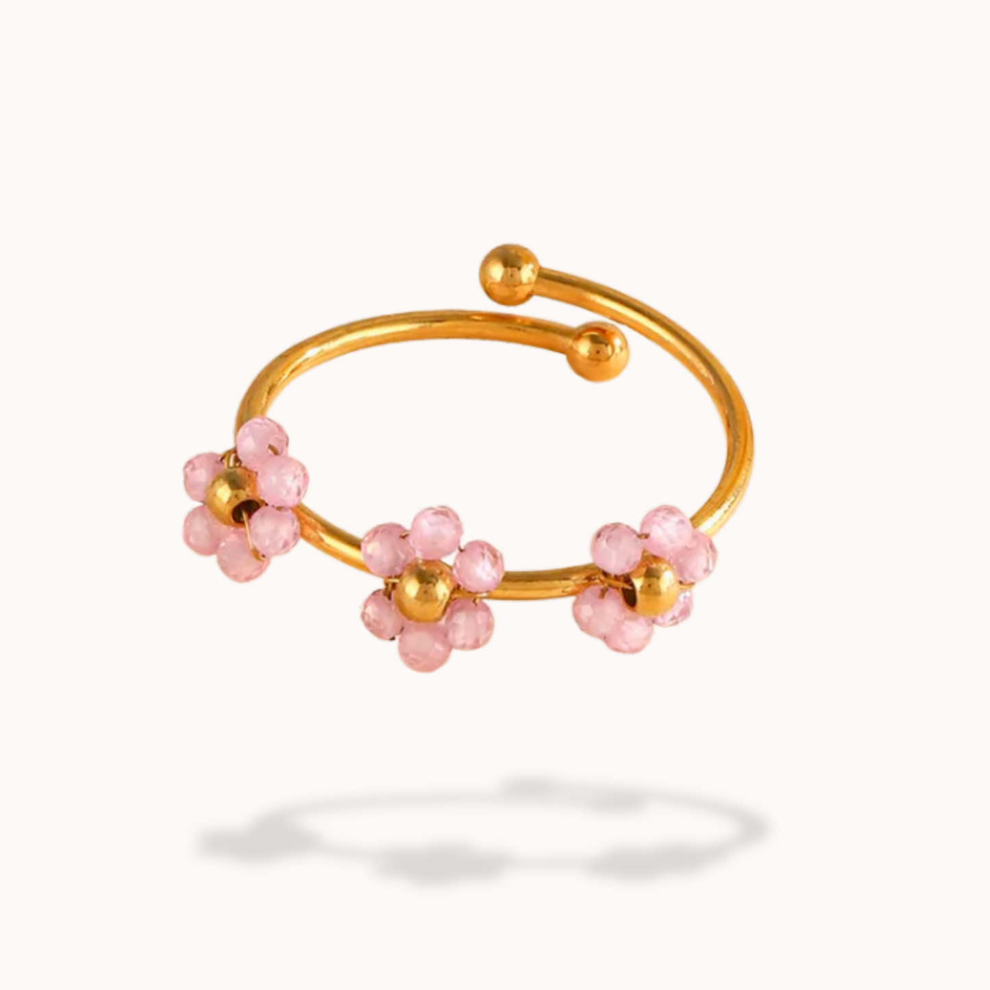 Gold bracelet with pink beads on a white background