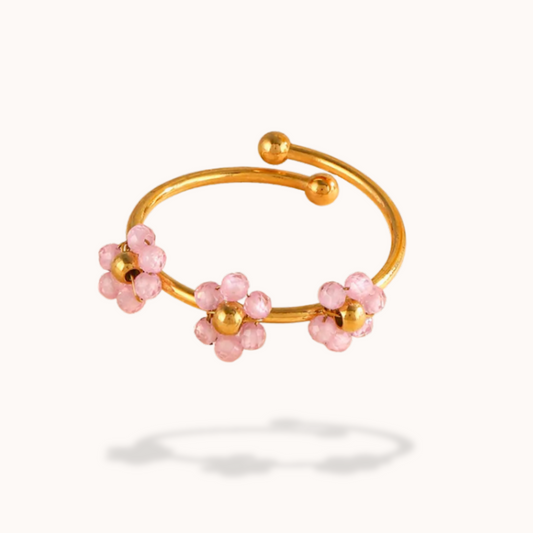 Gold bracelet with pink beads on a white background