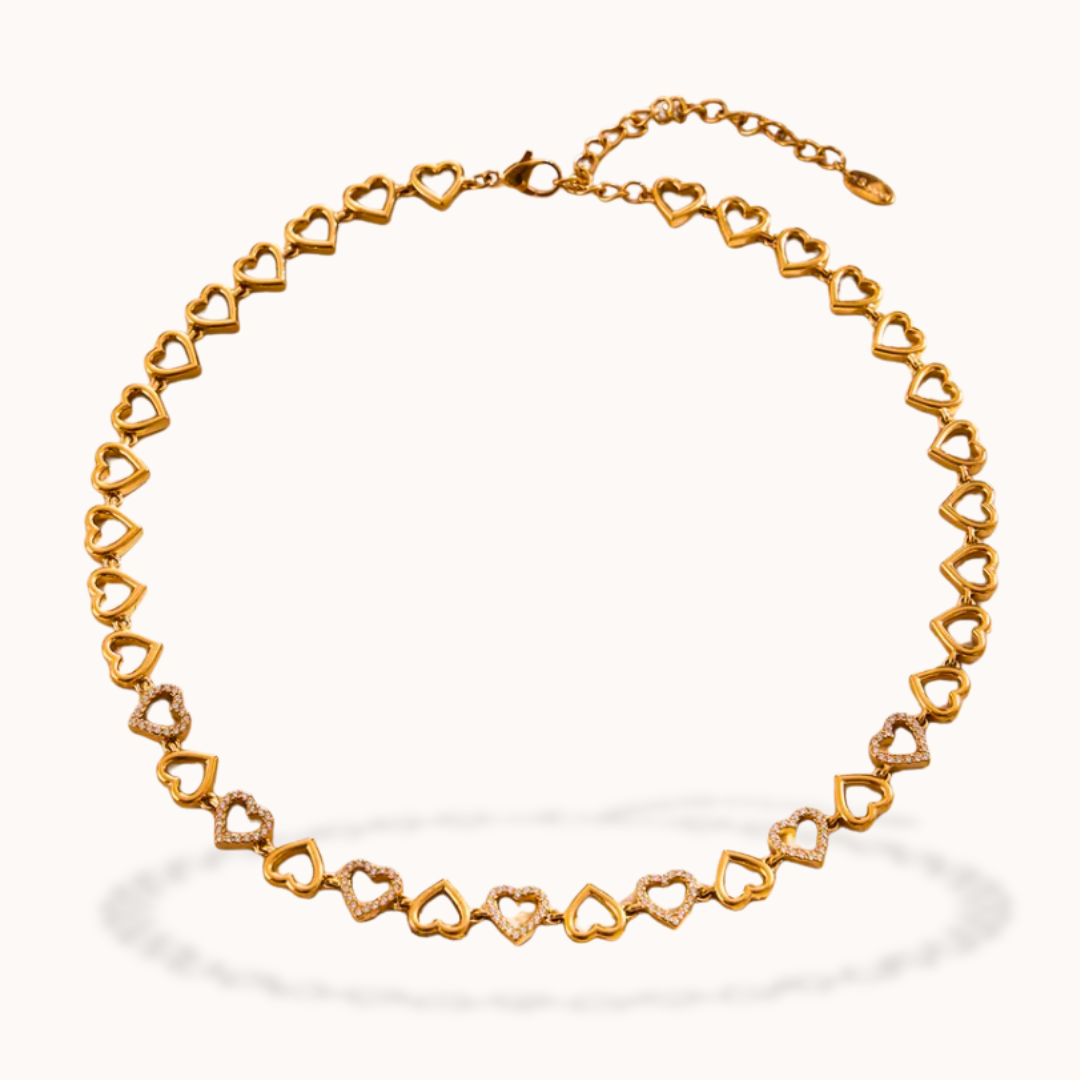 A gold heart-link chain necklace displayed on a clean, off-white background with a soft shadow underneath.