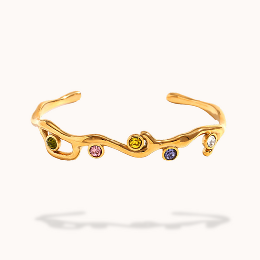 Gold bracelet with embedded colorful gemstones on a white background