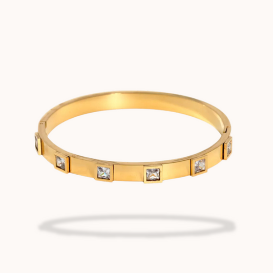 Gold bracelet with square gemstones on a white background