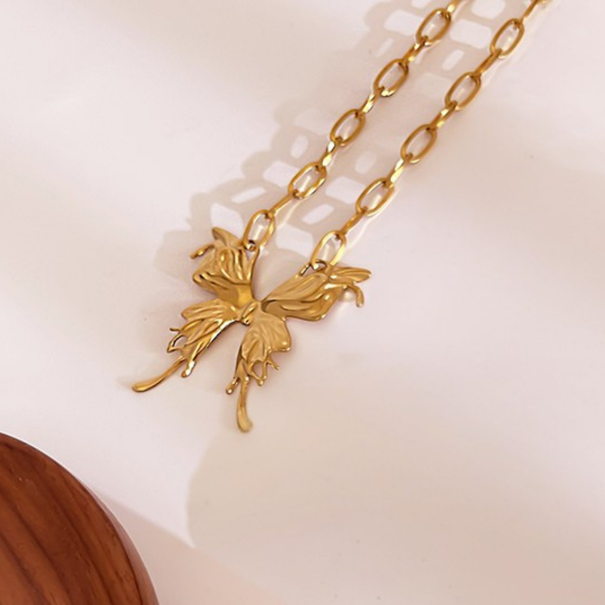 Gold fairy pendant necklace on a light pink background