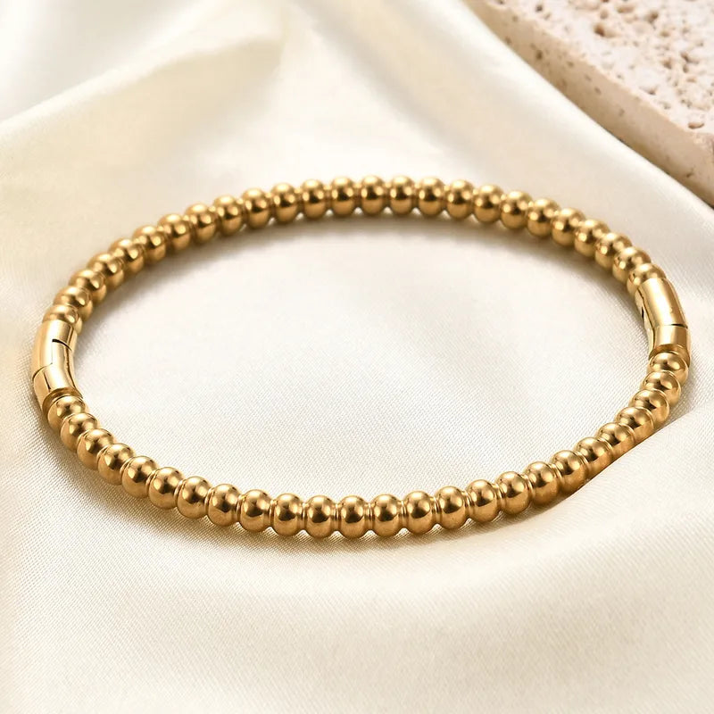 Gold beaded bracelet on a light beige fabric background