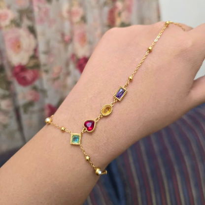 Gold bracelet with colorful gemstones on a wrist against a floral background