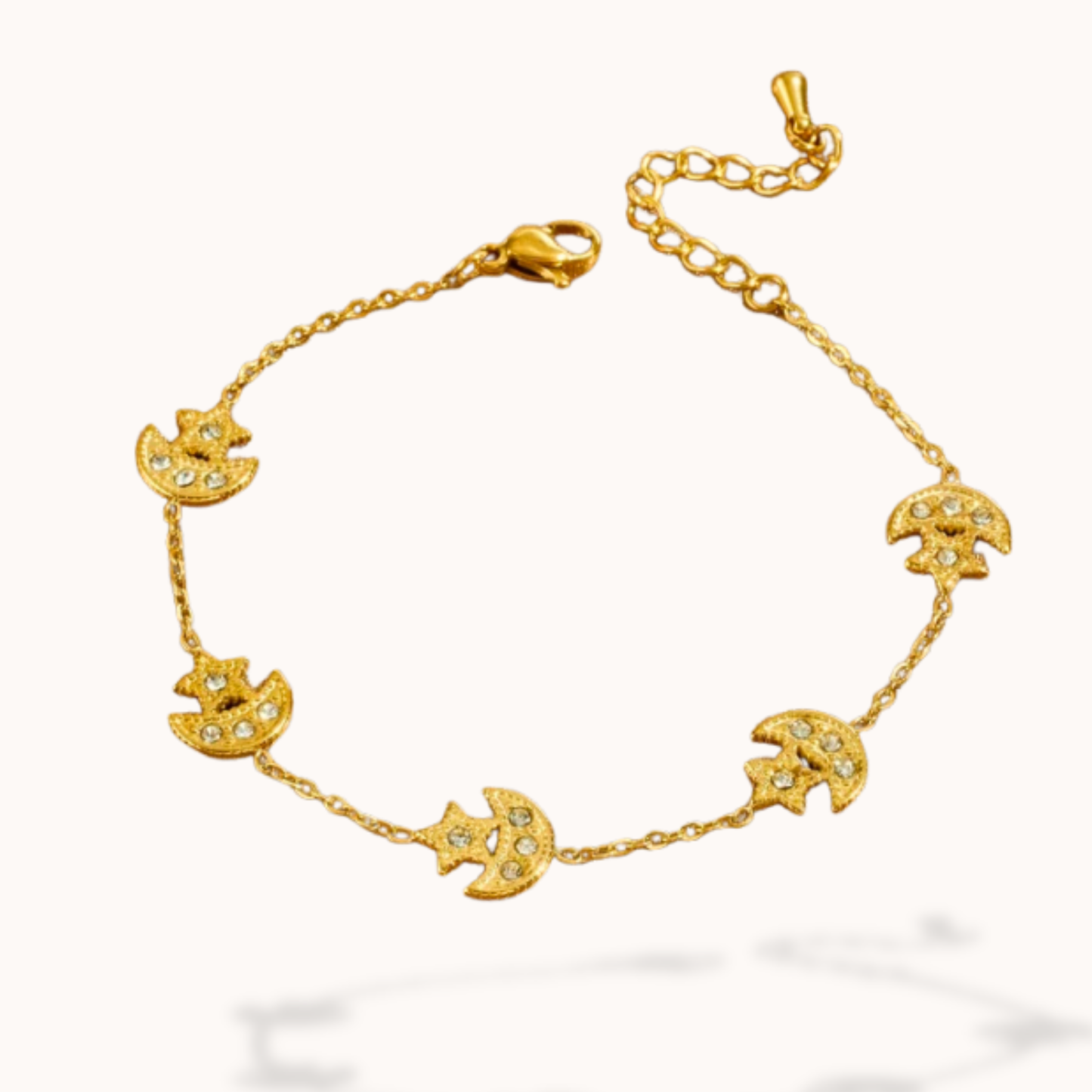 Gold bracelet with moon and star designs on a white background