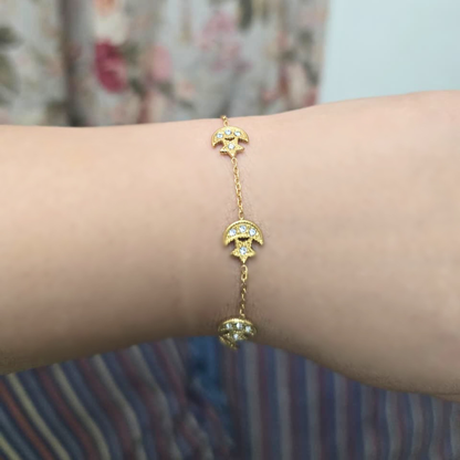 Gold bracelet with moon and star designs on a wrist against a blurred background