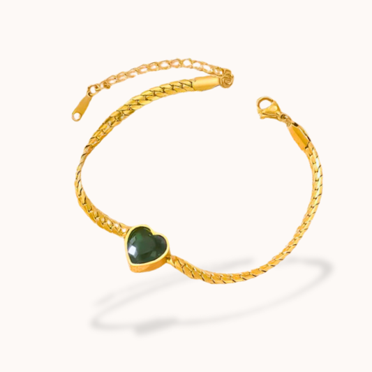 Gold bracelet with a green heart-shaped gemstone on a white background
