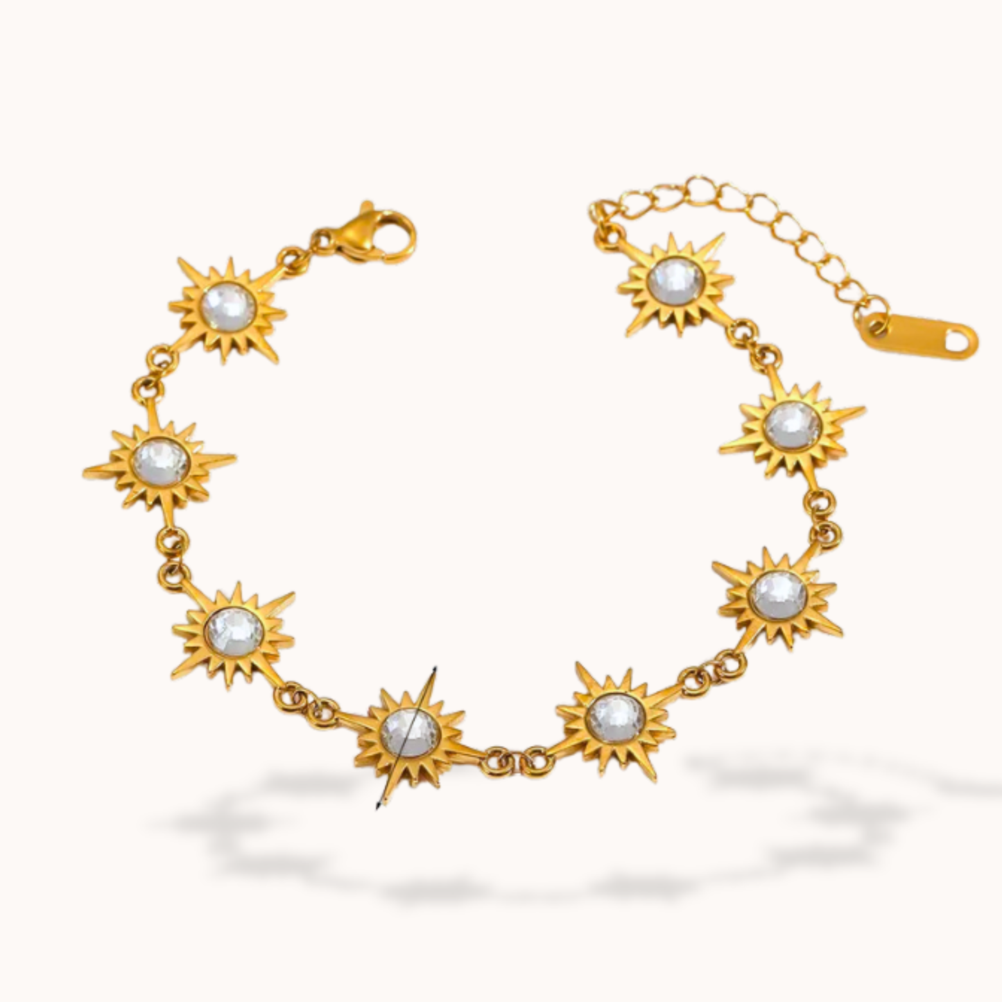 Gold bracelet with sun-shaped links and pearl-like centers on a white background