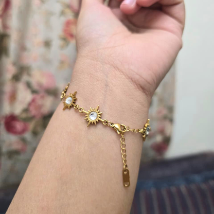 Gold bracelet with sun and moon designs on a wrist against a floral background