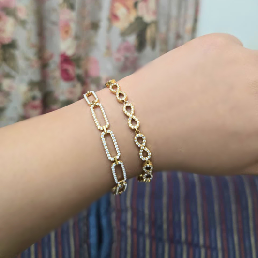 Gold chain bracelet on a wrist with a floral background
