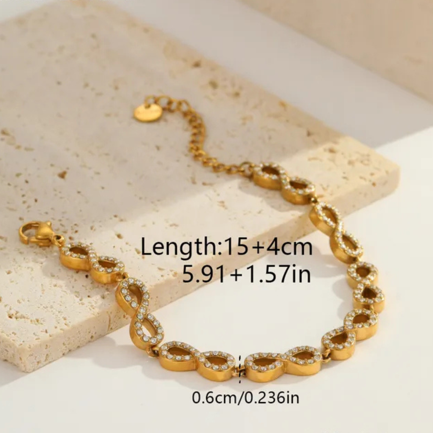Gold bracelet with heart-shaped links on a beige stone surface