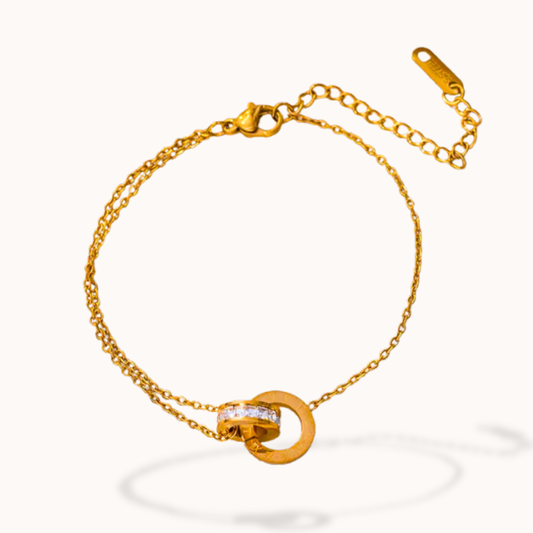 Gold bracelet with a circular clasp on a white background
