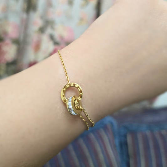 Gold bracelet with a circular design on a wrist against a floral background
