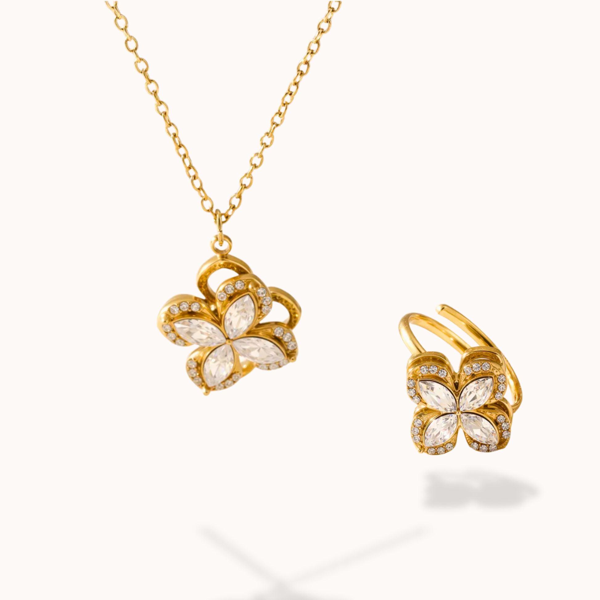 clover-shaped gold necklace and ring on a white background