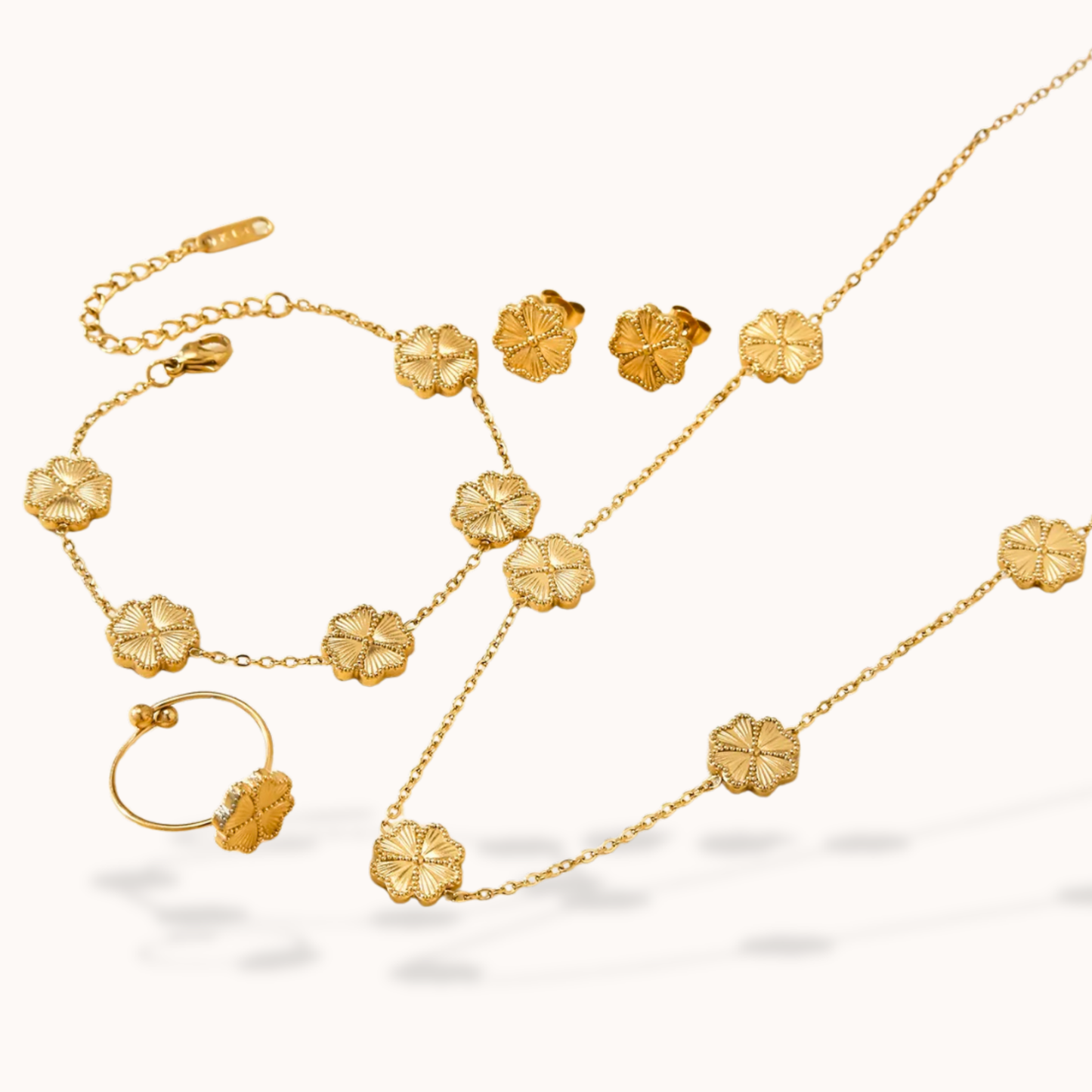 Gold jewelry set with necklace, earrings, and ring on a white background