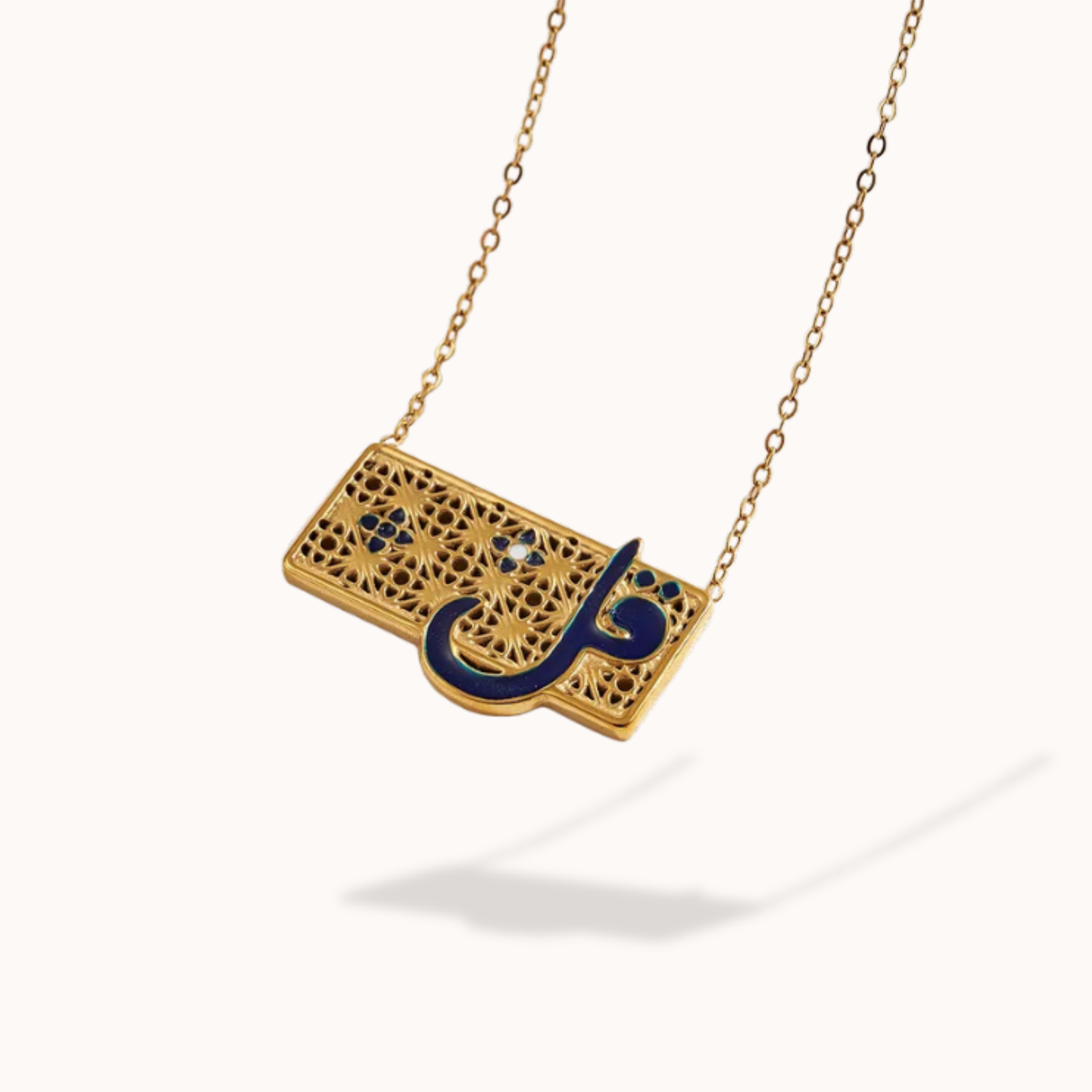 Gold necklace with a rectangular pendant featuring Arabic calligraphy in black on a white background
