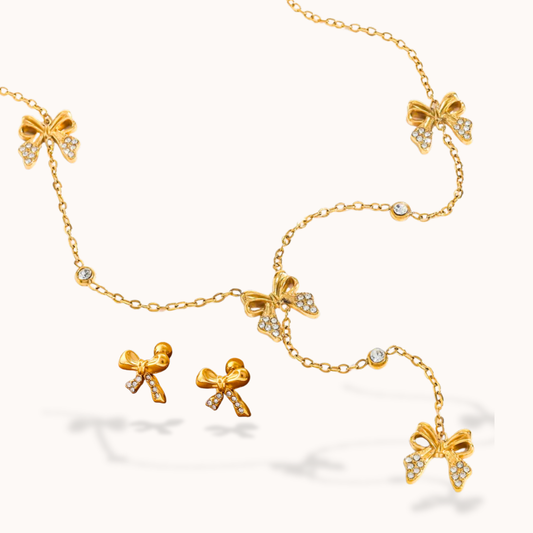Gold bow-shaped jewelry set on a white background