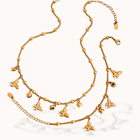 Gold necklace with various charms on a white background