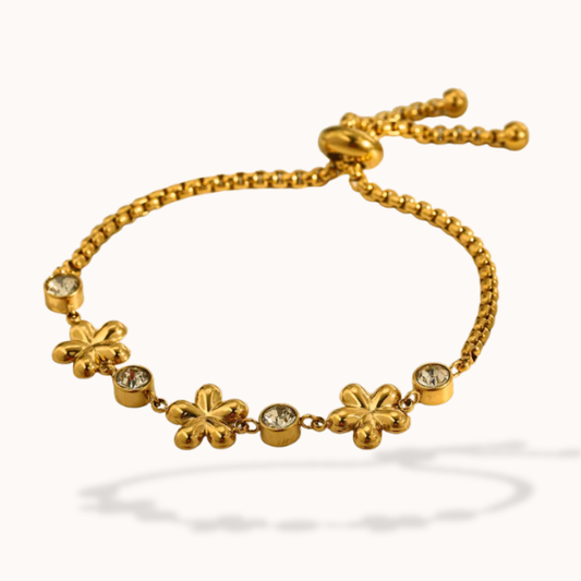 Gold bracelet with floral charms on a white background