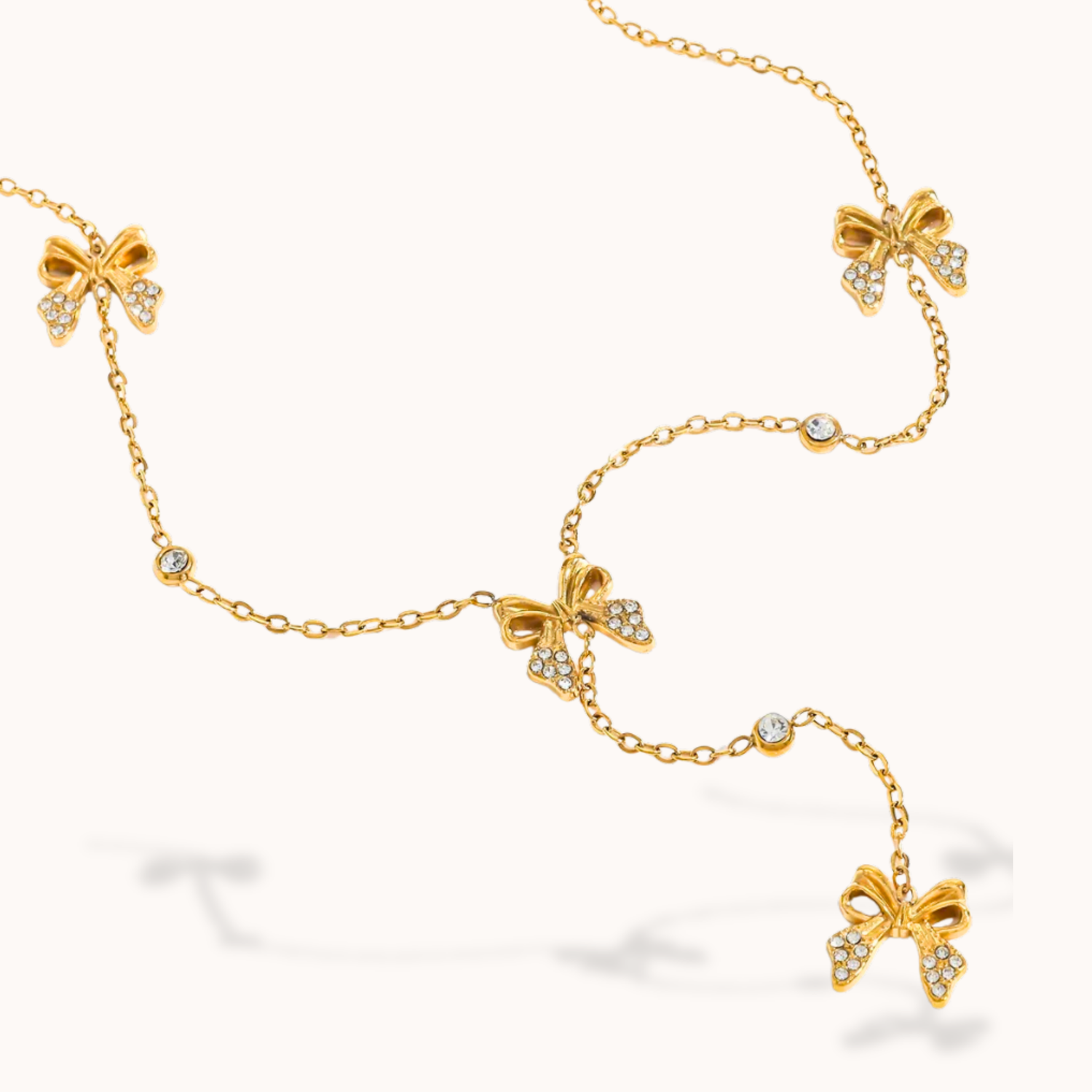 Gold bracelet with bow-shaped charms on a white background