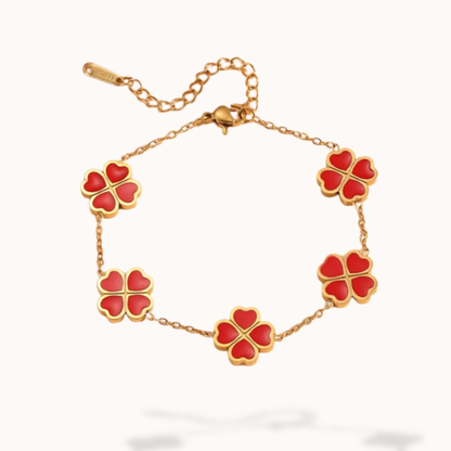 Gold bracelet with red clover-shaped charms on a white background