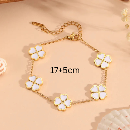 Gold bracelet with four-leaf clover charms on a beige background