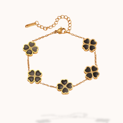 Gold bracelet with black clover-shaped charms on a white background