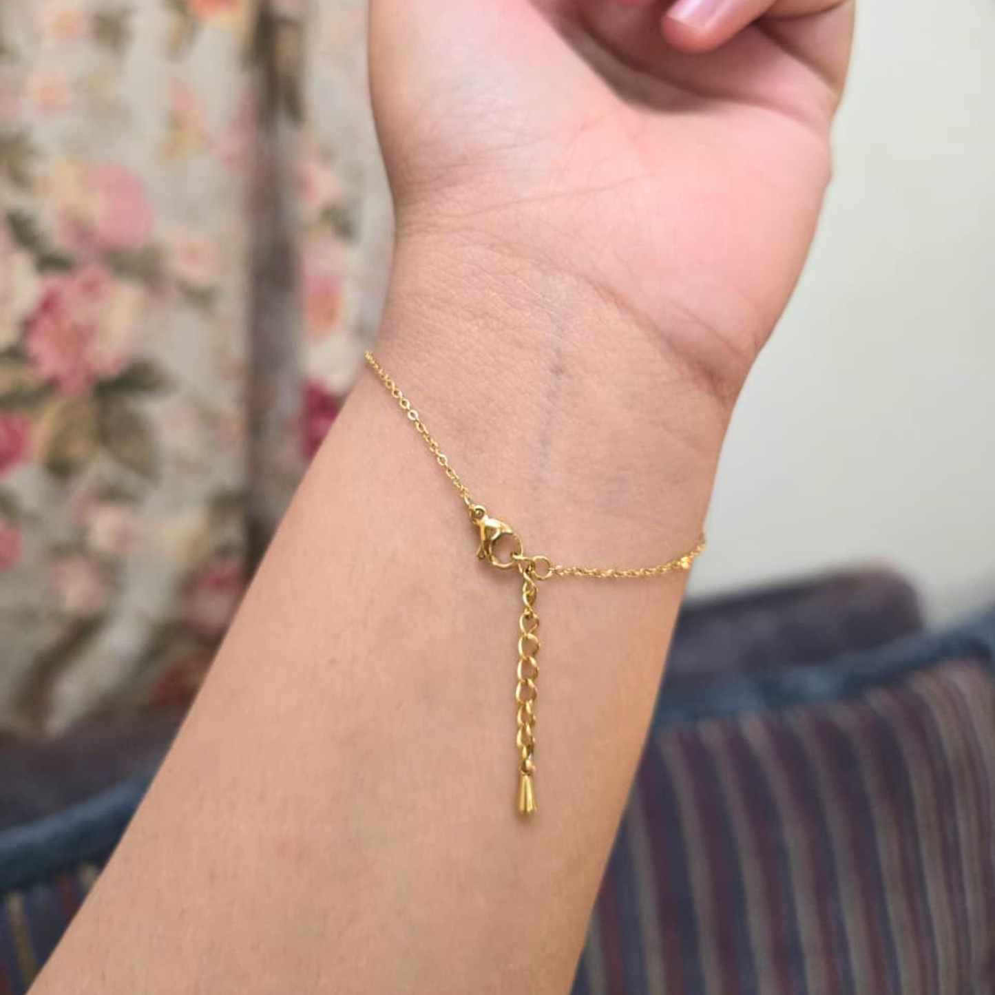 Gold bracelet on a wrist with a floral background