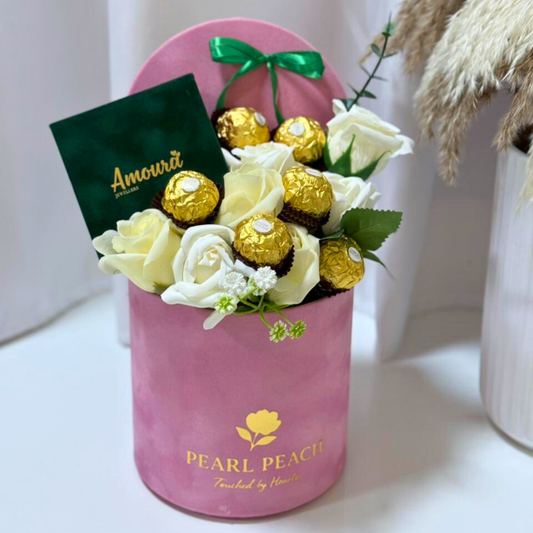 Pink box with white and gold roses and chocolates on a white background