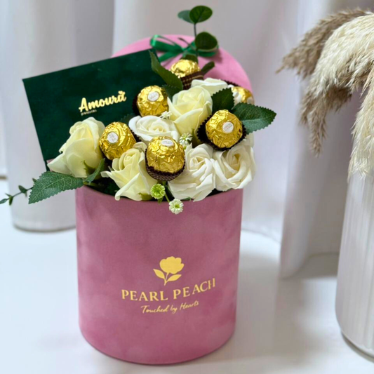 Pink box with white and gold roses and chocolates on a white background
