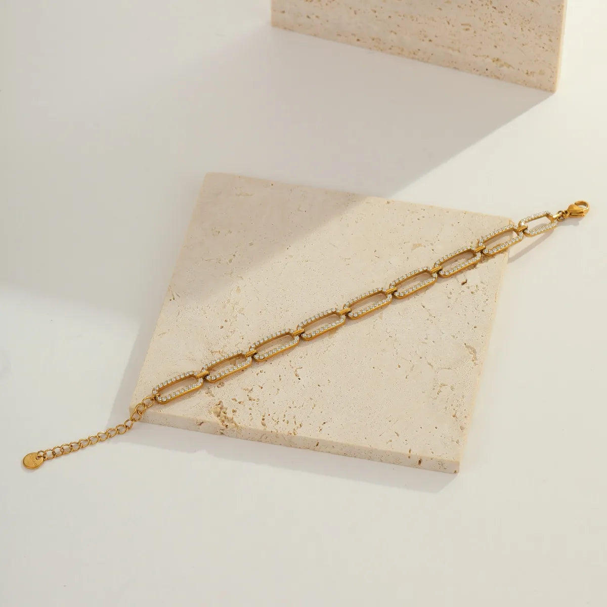 Gold chain bracelet on a beige stone surface