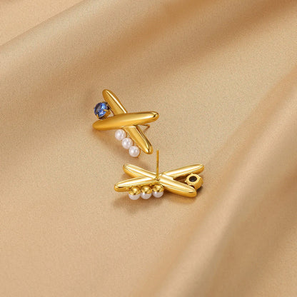 Gold earrings with pearls and gemstones on a beige fabric background