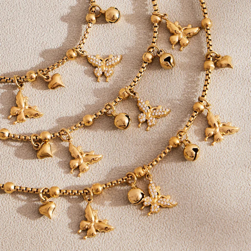 Gold necklace with various charms on a light beige background