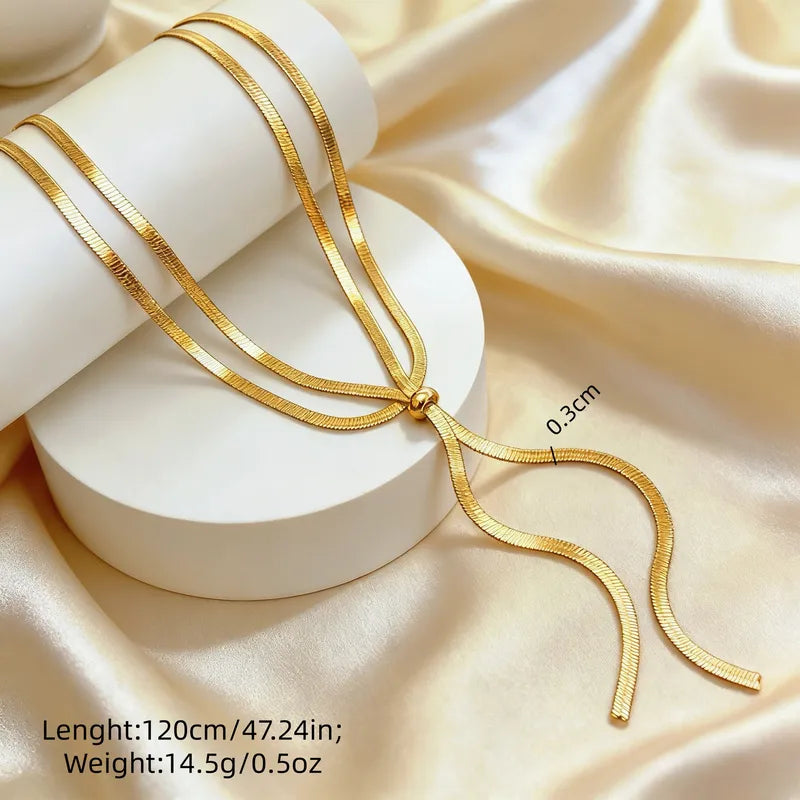 Gold necklace on a white stand with beige fabric background