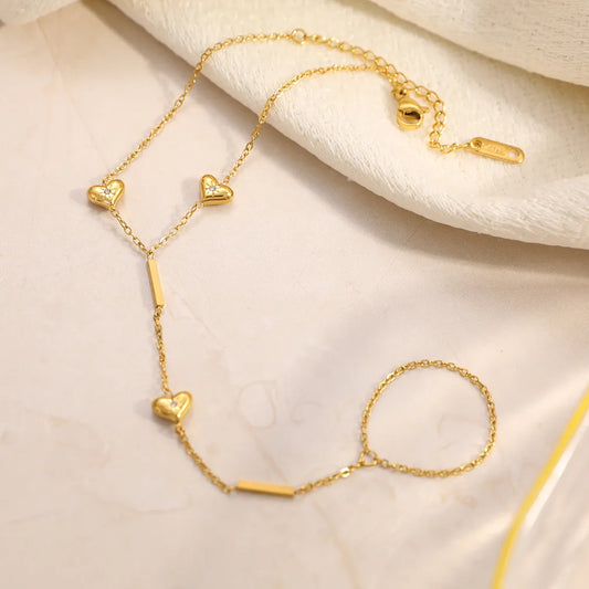 Gold bracelet with heart-shaped charms on a beige fabric background