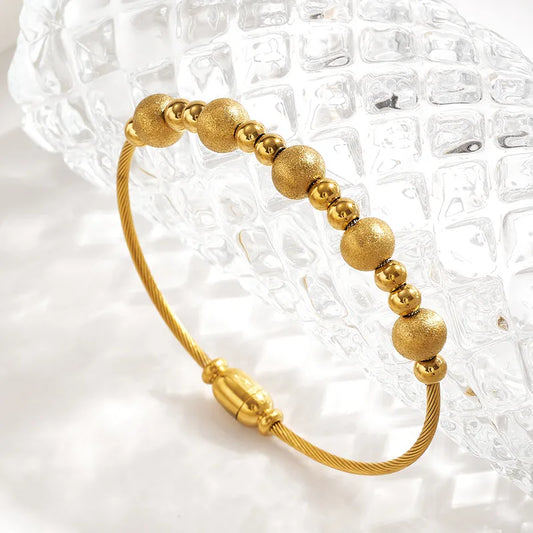 Gold beaded bracelet on a textured white background