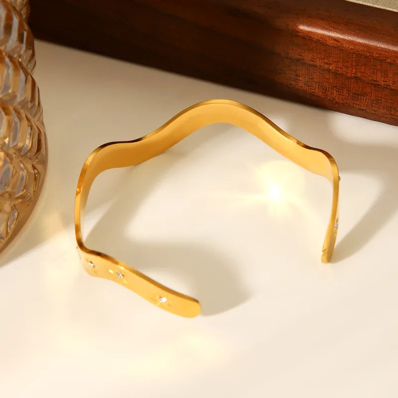 Gold decorative item on a white surface with a wooden box in the background