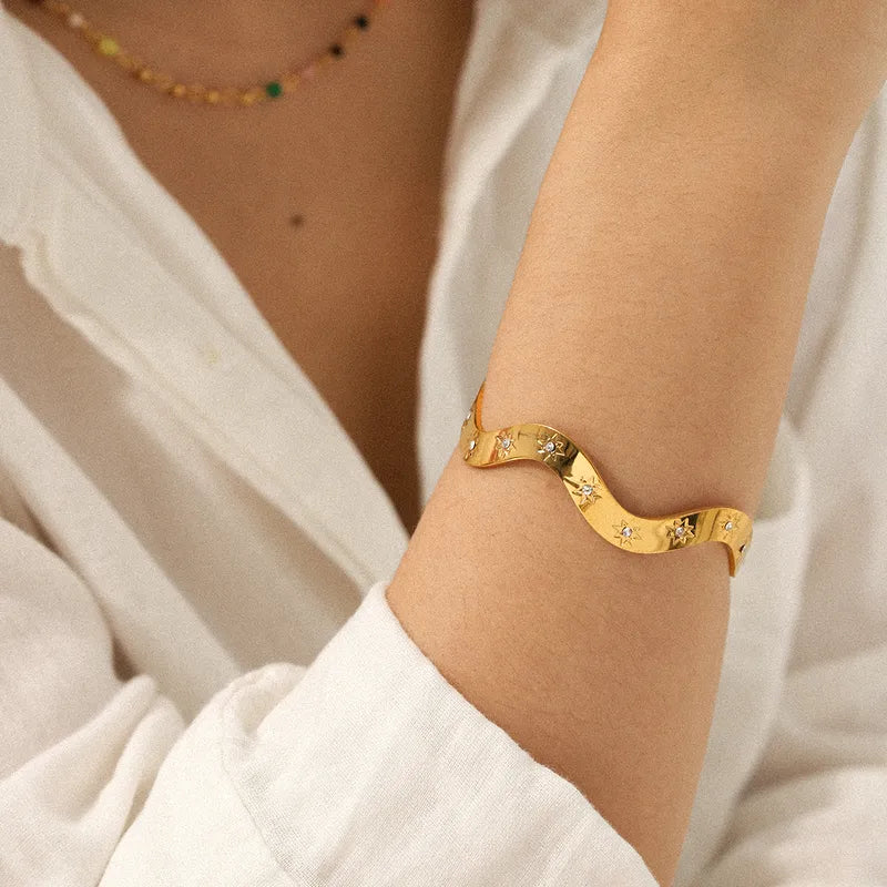 Gold bracelet on a person's wrist with a neutral background