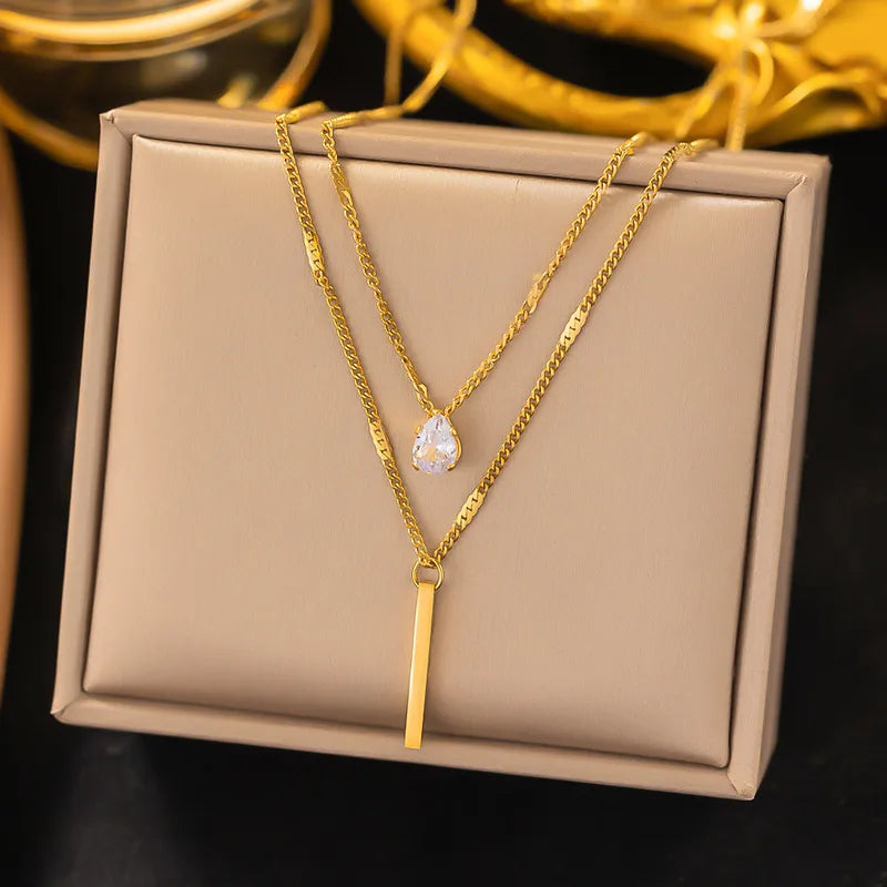 Two gold necklaces on a beige jewelry box with a dark background
