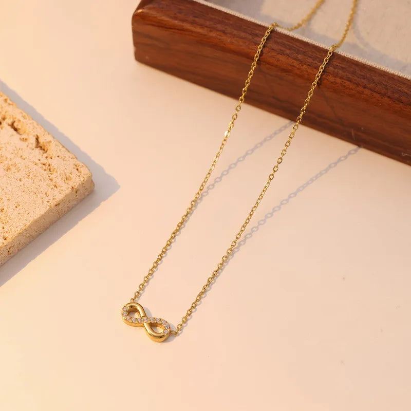Gold necklace with an infinity symbol pendant on a light surface