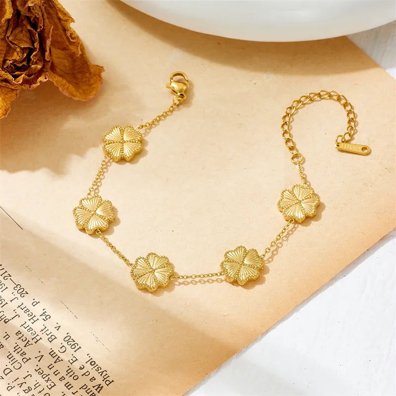 Gold bracelet with floral designs on a beige surface