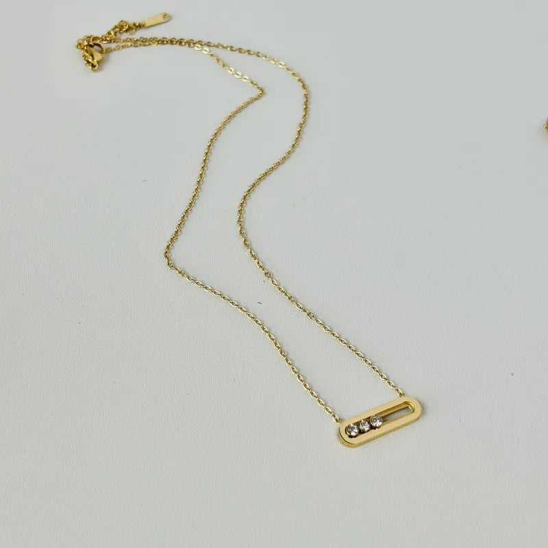 Gold necklace with a small pendant on a light gray background