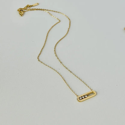 Gold necklace with a small pendant on a light gray background