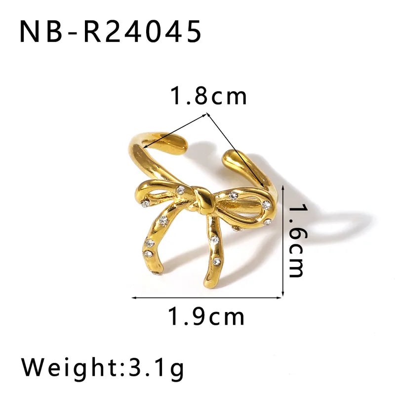 Gold bow-shaped ring with measurements on a white background