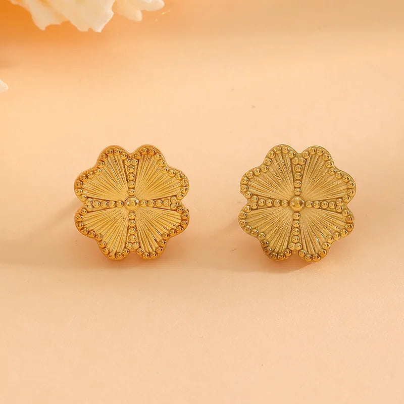 Pair of gold floral earrings on a beige background